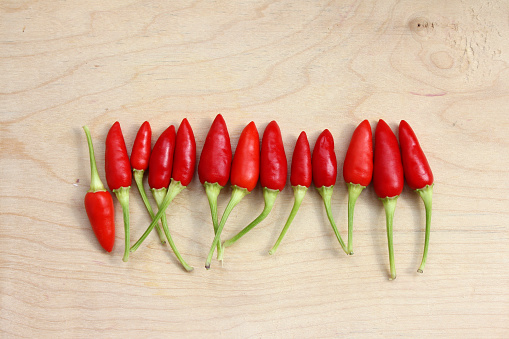 Red hot chilli peppers in a row on the wood background